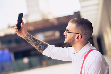 Businessman taking self portrait with iphone. Young hipster man
