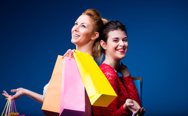 women shopping with lots of bags on blue