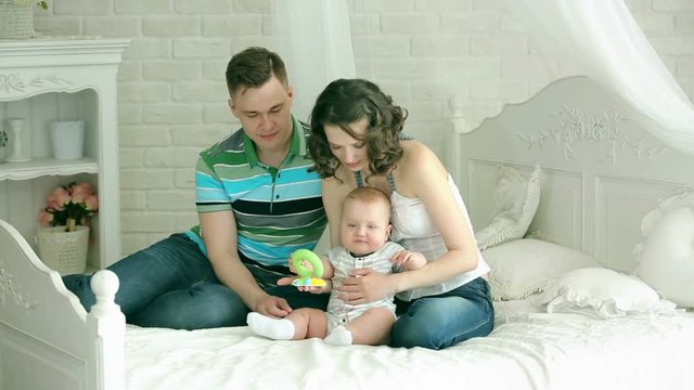 Mom dad and 6 month old baby. Happy family playing with a child. Family play with infant.