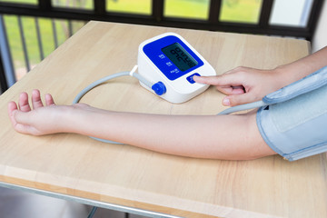 Concept of female press start button on blood pressure in room