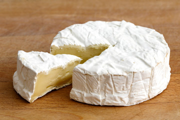 Fototapeta na wymiar White mould cheese with cut slice isolated on wood board.