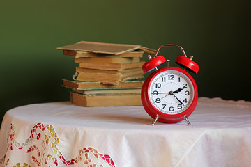 Red retro alarm clock on table with white tablecloth.