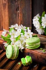 Green color Macaroons with spring flowers on wooden vintage background. Selective focus