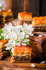 Walnut baklava on wooden vintage background with spring flowers. Arabic cuisine. Selective focus