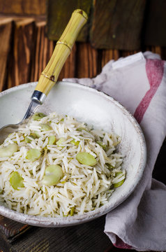 Rice pilaf with fava beans on wooden background. Selective focus