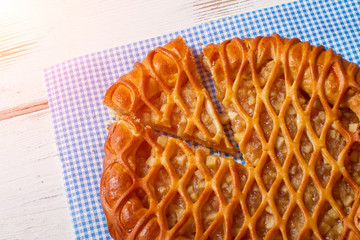 Sliced pie laying on napkin. Pie on white wooden background. Delicious pastry with fruit filling. Tasty organic meal.