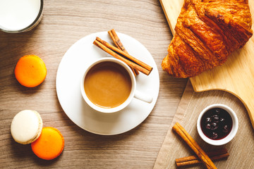 sweet breakfast with coffee, macaroons and croissants on wooden table