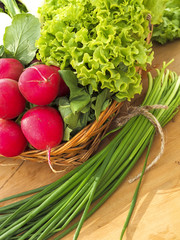 Spring vegetables in basket: radish, cucumber, chives and cauliflower
