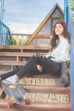 Hipster skateboarder girl with skateboard outdoor at skatepark