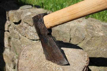 Axe stuck in the log, stone wall in the background