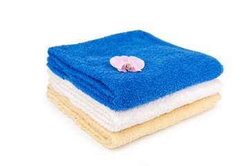 Stack of towels and orchid on a white background.