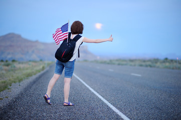Young female tourist hitchhiking along a desolate road