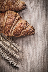 Composition of golden wheat rye ears sweet croissants on wooden 
