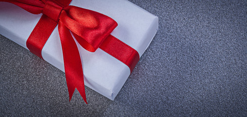 Present box with red knot on grey surface holidays concept