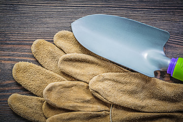 Shovel pair of safety gloves on wooden board directly above gard