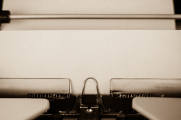 Sepia version of a detail view of a sheet of parchment paper in a typewriter, circa 1970.  Paper...