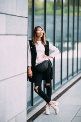 Fototapeta premium Street fashion concept - pretty young slim woman in rock black style posing against the wall