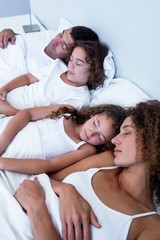 Family sleeping together on bed