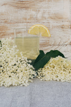 Glass of  elderflower juice and elder-flowers