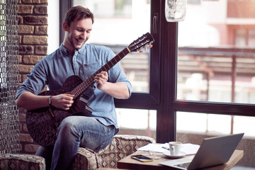 Positive  smiling man playing the guitar   