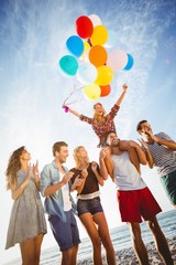 Friends dancing on sand with balloon