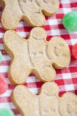 cropped image of gingerbread candies arranged over red checkered tablecloth.