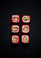 Philadelphia Roll with caviar, top view, a dark stone background