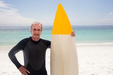 Portrait of senior man in wetsuit holding a surfboard