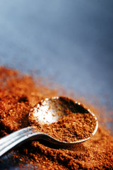 Ground chili pepper in a spoon on a dark background, macro shot,