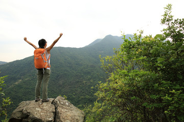 Obraz premium cheering woman hiker open arms on mountain peak