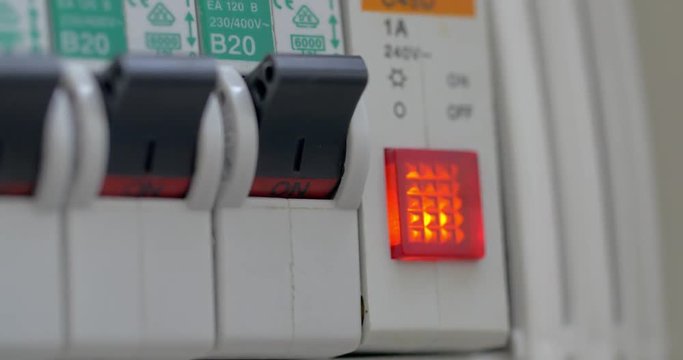 Close-up shot of female hand turning on the water heater. She shifting switch on power panel and light indicator turns red. Electricity saving
