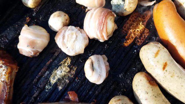 Bacon wrapped champignons, on a barbeque, with sausages, bratwurst, meat and ribs