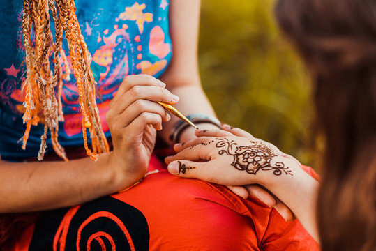 Picture of human hand being decorated with henna tattoo, mehendi