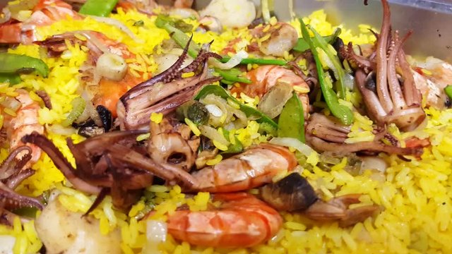 Closeup on a seafood paella, with octopuss, shrimp, scallops and salmon, at a restaurant kitchen
