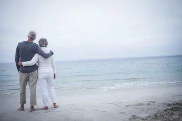 Fotobehang Rear view of senior couple embracing on beach © WavebreakmediaMicro