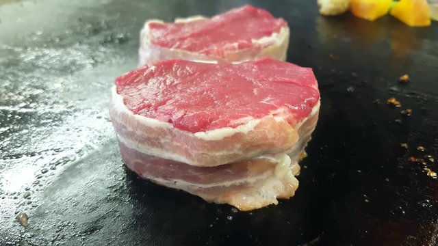 Frying bacon wrapped, filet mignon tournedos steaks, at a restaurant kitchen
