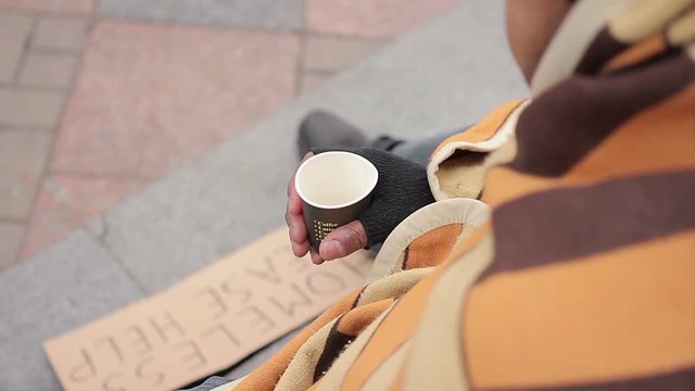 Poor person begging for charity in city street, sympathetic people giving money