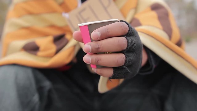 Poor Man Holding Out Hand With Paper Cup To Camera, Asking For Help And Charity