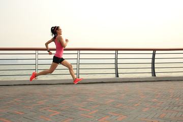 young fitness woman runner running on seaside