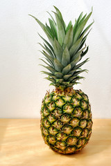 Pineapple on wooden table with white wall 