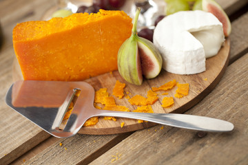 image of cheese slicer, cheese and fig.