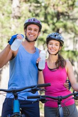 Naklejka premium Portrait of young couple drinking water at forest