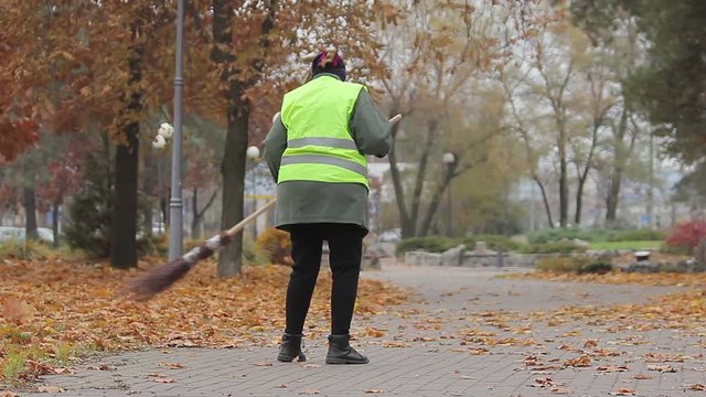 Female municipal utility worker sweeping street, low paid job, poverty
