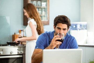 Man having red wine and using laptop
