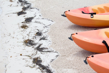 End of three orange sea kayaks on the sand beach - Powered by Adobe
