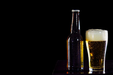 Bottles of beer and glass getting cool on black  background