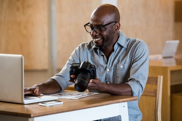 Man holding camera while using laptop