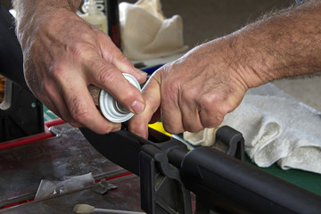 Gunsmith spraying solvent into lower assembly of 20 gauge pump action shotgun