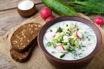 Okroshka on kefir with rye bread on a wooden table