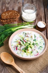 Okroshka on kefir with rye bread on a wooden table
